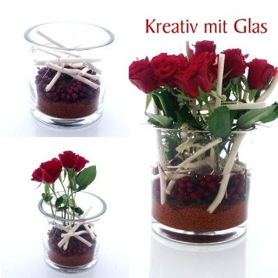 Große Glasvase für die Tischdekoration mit Rosen, Dekosand, Beeren und Zweige dekoriert.